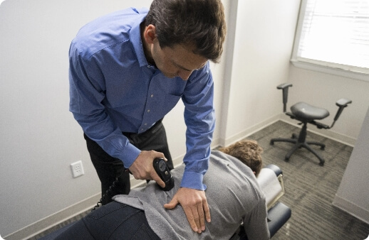 Dr. Todd administering the percussor on a patient's lumbar spine