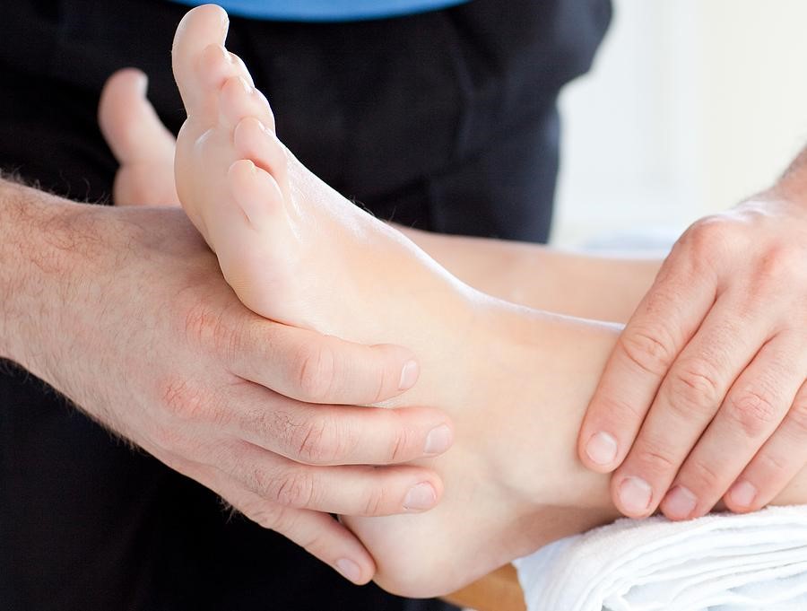 A medical professional evaluating a bare foot for plantar fasciitis